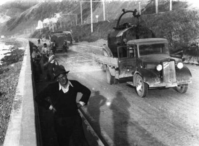 The man in the foreground is thought to be JR McLauchlan, the contractor whose truck is seen on the right. Behind him are Joe Ropata, Reg Fielding and Fred Strand putting "chips" on the road surface for Centennial Highway, 1939. HP 1091 J Beattie Collecti