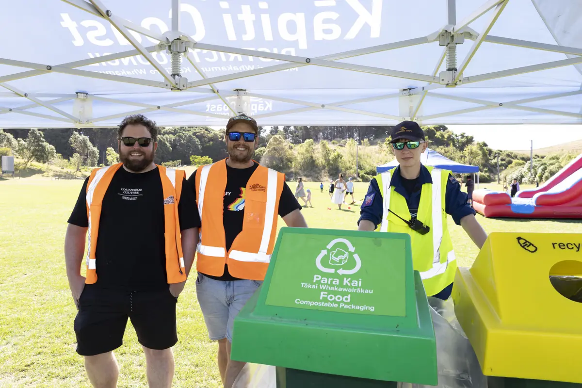 Two members of our waste team and an Air Cadet stand behind recycling bins at one of our community events.