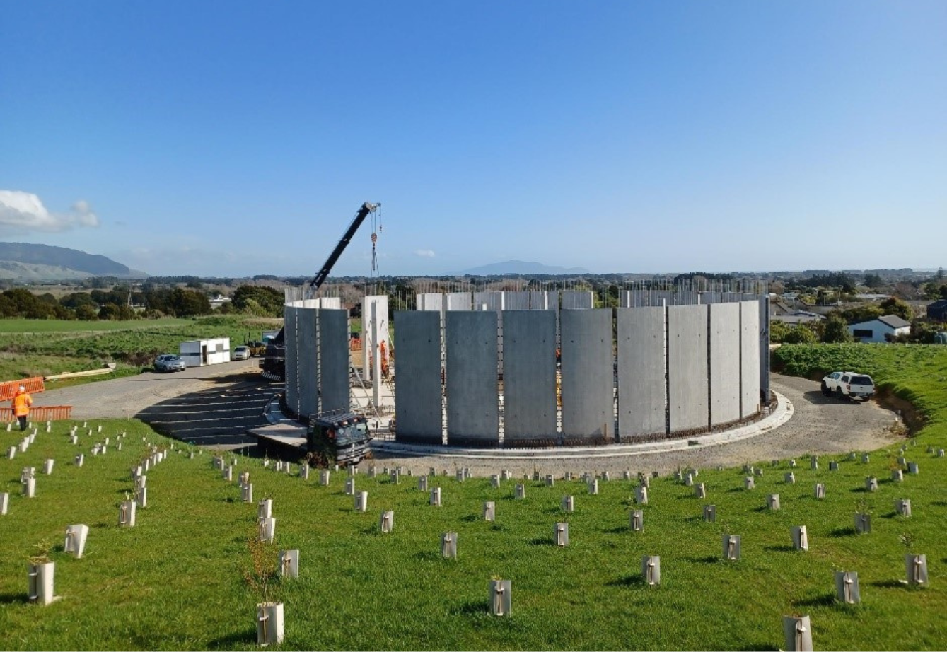 A crane puts the last wall panel in place on the Ōtaki Reservoir and the bund around the reservoir has been planted with native plants.