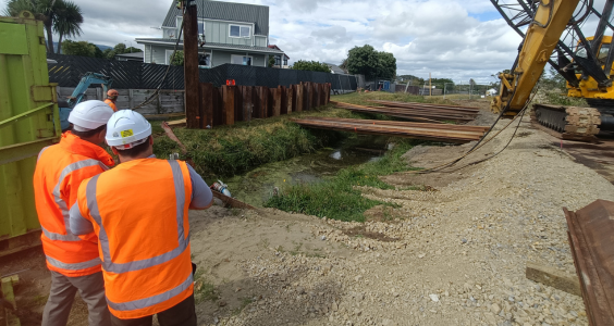 Chief Executive Darren Edwards in hard hat and high vis vest with contractors and heavy machinery at the Kenakena stormwater relief project.