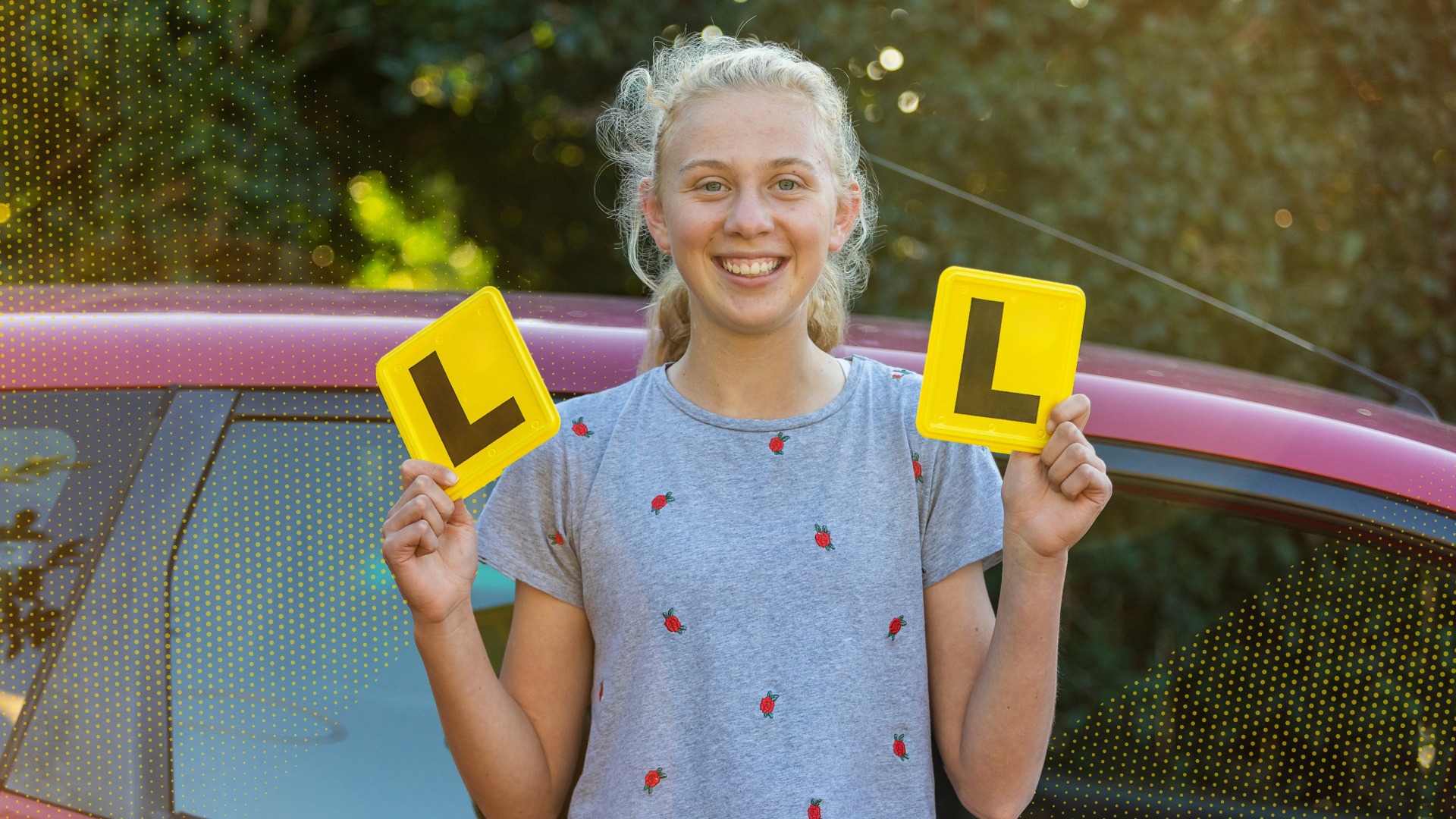 A young girl proudly holds her learner plates.