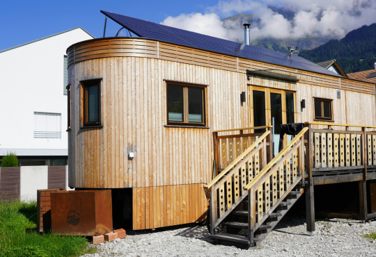 Photo of a wooden tiny home with solar panels on the roof.