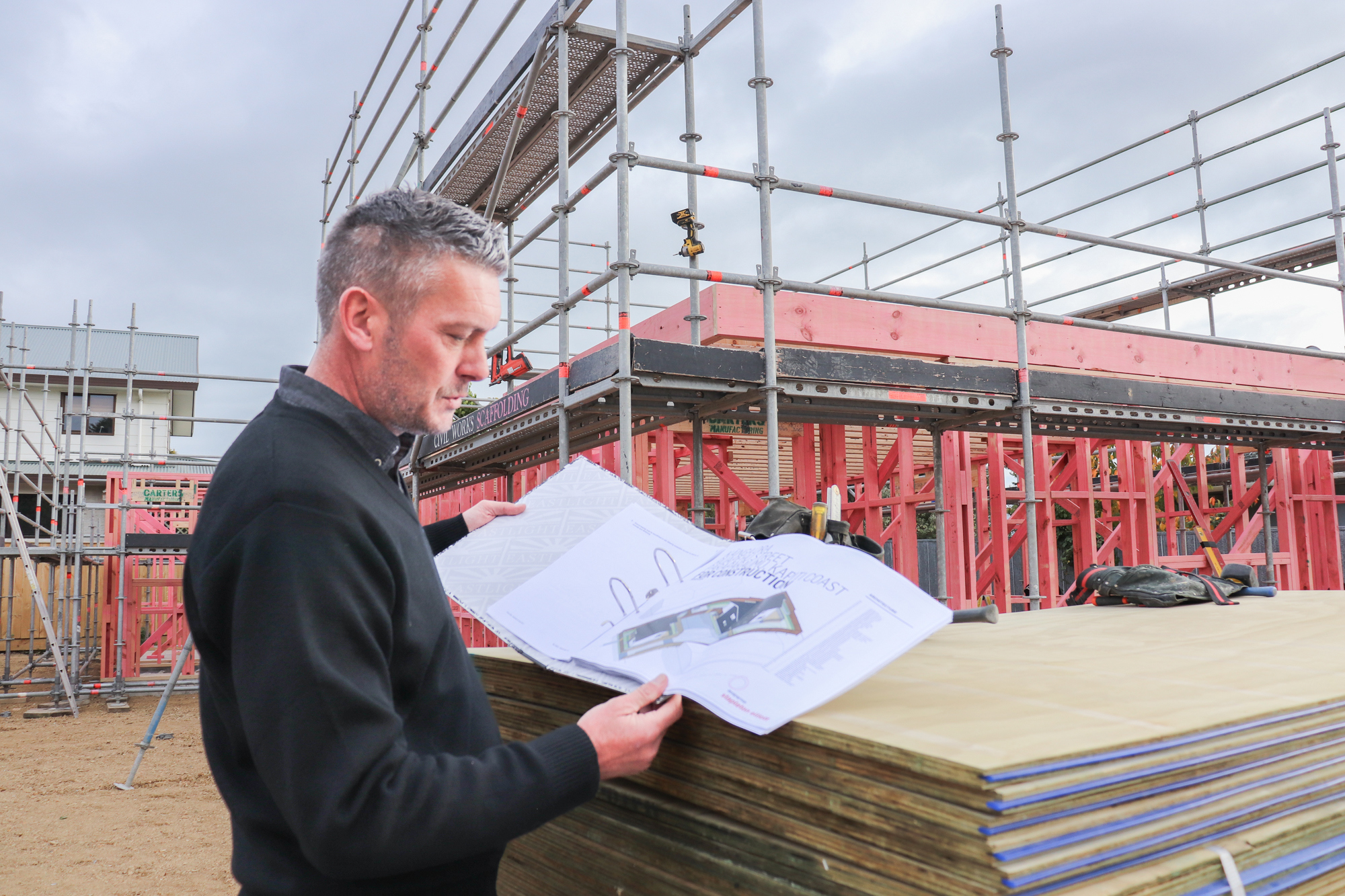 A man reads detailed plans on a building site.